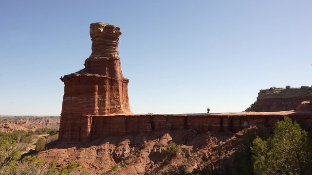 Hiker Walks Palo Duro Lighthouse Rock Structure in Palo Duro Canyon State Park Wide Landscape Hoodoo Formation Texas