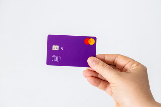 Hand holding Nubank credit card with contactless payment chip and Mastercard logo. Digital banking and fintech concept