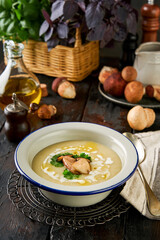 Cream soup with porcini mushroom homely atmosphere on rustic wooden kitchen table with cutting board, ingredients and kitchen utensils. Autumn harvest concept. Style rustic.