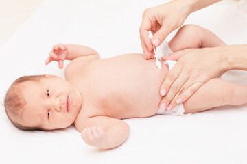 Mother wipes newborn baby navel with cotton swab