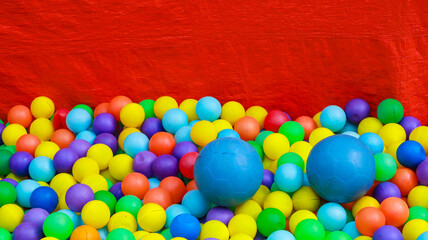 A close up of a pit full of brightly colored plastic balls against a red background. Colorful Plastic Balls in a Red Pit.
