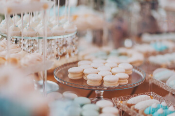 Beautiful cakes and cookies. Wedding candy bar. Delicious creamy desserts with fruits, macarons, cakes and cookies on table at wedding reception in restaurant. Luxury catering service.