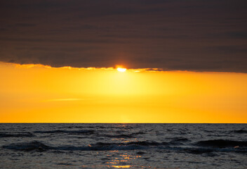 A beautiful sunrise over the Baltic sea - horizon and colorful sky. Natural summer scenery at the Baltic beach in Latvia, Northern Europe.