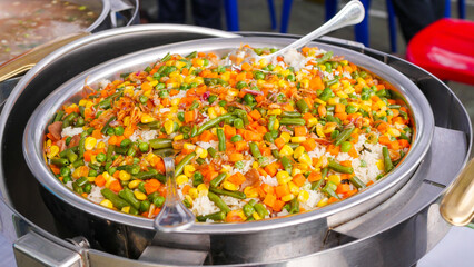 A steaming pot of rice with mixed vegetables ready to be served at gathering events.