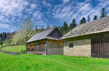 Obraz premium Old wooden agricultural buildings at the mountains in springtime.