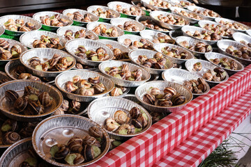 Escargots de Bourgogne, typical French dish of snails with butter and garlic, on small plates at a food stall.