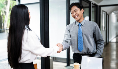 Two happy diverse professional businessmen and businesswoman executive leaders shaking hands at office meeting.