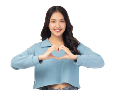 Young woman smiling and forming a heart shape with her hands, looking at camera