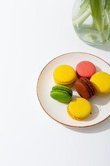 Colored macarons on a plate on a white table