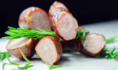 A pile of sausages with rosemary on top