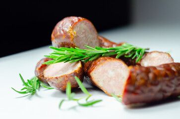 A pile of sausages with rosemary on top