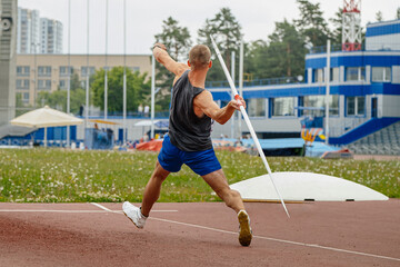 Obraz premium male athlete javelin throw rear view at summer athletics games