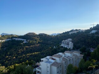 Naklejka premium Evening night view of Altea Hills, Spain, hills, houses, villas, trees, the Mediterranean Sea, clouds, dramatic sky, streetlights, urbanization, late evening.
