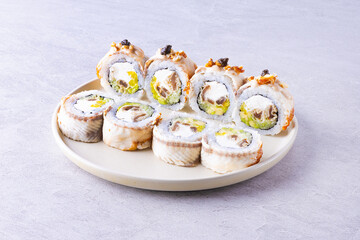 Set of sushi rolls dragon on a black matte plate. Japanese traditional sushi dish with avocado, eel and soy sauce. A beautiful dish for an Asian restaurant menu