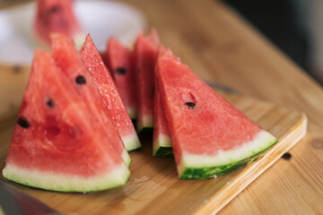 Cutting into triangular pieces watermelon on a wooden cutting board.