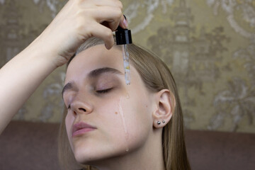 Girl drips special moisturizing oil on her face for skin care