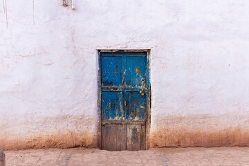 Façade with blue weathered door of adobe style building in San Pedro de Atacama, Antofagasta, Chile in center of characteristic city in Atacama Desert