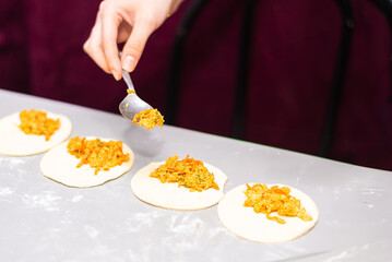 Pieces of chicken are placed on the puff pastry dough. Preparation of chicken patties from puff pastry dough. Close-up detail. 