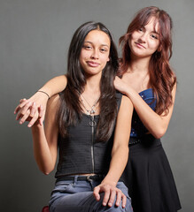 Portrait of two teenage women holding hands and looking at the camera, the girls are Latins are happy and show the value of friendship and complicity. They are fashionably dressed in casual clothes.