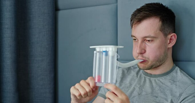 A young man tests his lungs using a spirometer.
