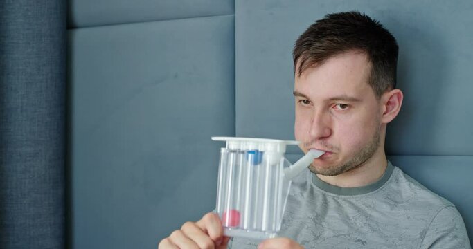 A young man tests his lungs using a spirometer.
