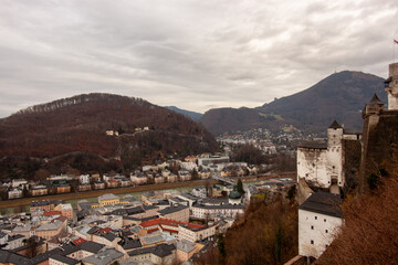 Obraz premium Panoramic view of the old town and mountains from the Hohensalzburg fortress. Cloudy and gloomy winter day