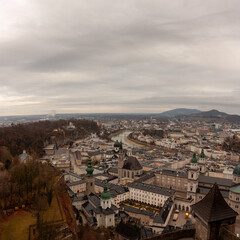 Obraz premium Panoramic view of the old town from the Hohensalzburg fortress. Cloudy and gloomy winter day, St. Peter's Abbey and Baroque Salzburg Cathedral