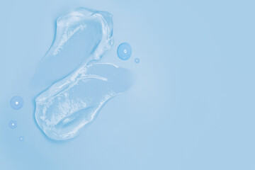 Gel smears and drops of cosmetic texture on blue background with space for text