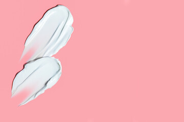 creamy strokes of white cosmetic texture on pink background with space for text