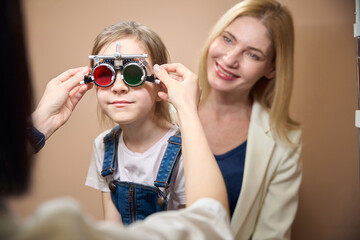 Woman ophthalmologist checks a child eyes using a special gadget