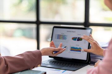 Two people are looking at a computer screen with a lot of graphs and charts