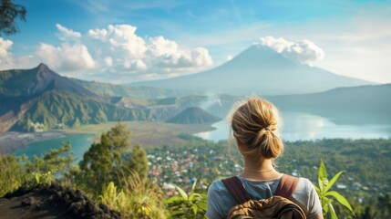 A lone woman traveler stands on a mountainside overlooking a stunning vista of lush green valleys, a serene lake, and the majestic Mount Batur in Bali