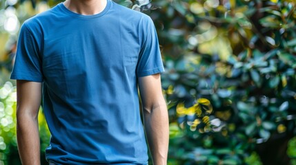 Naklejka premium A man in a blue t-shirt stands in a green, leafy garden