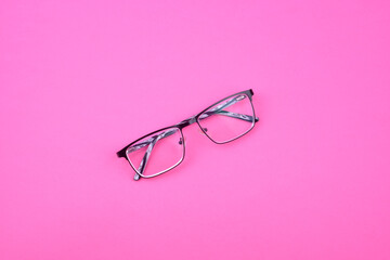 Black-white sight glasses with clear lenses on pink surface.