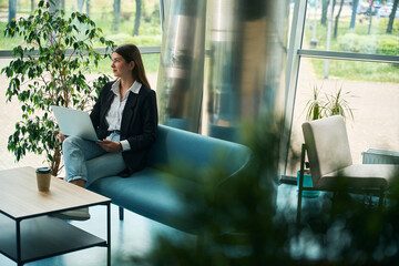 Caucasian woman sitting on sofa in coworking space