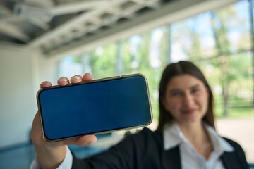 Young brunette holding phone with screen to camera