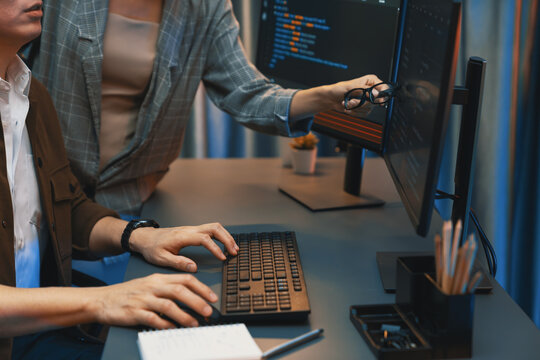 IT developers discussing with point to intelligent website development coder system running data online two screens information technology at neon light room at modern office. Infobahn.