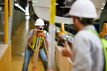 worker or engineer using theodolite surveying optical instrument for measuring at construction...