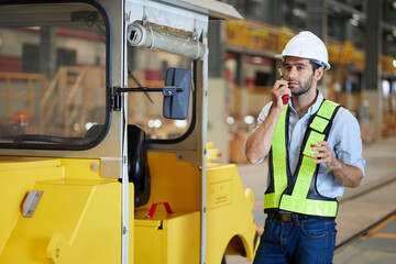 Engineer or worker talking on walkie talkie with a car in the factory