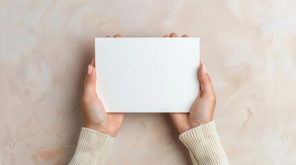 Hands holding a blank white book against a beige background, ideal for mockups, presentations, or visual content creation.