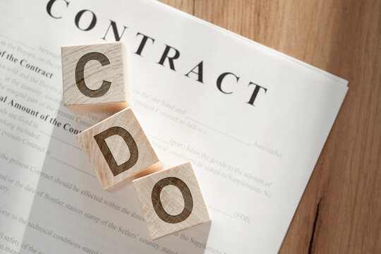 Wooden blocks spelling out CDO on a contract paper, indicating the importance of the Chief Data Officer in business.