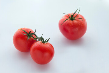 Three large and one small tomato on a white background
