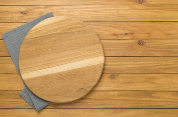 Cutting board with napkin on wooden background, top view