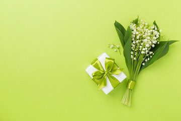 Lilies of the valley with gift box on color background, top view
