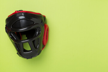 Black leather boxing helmet on color background, top view.