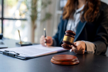 A woman in a suit holding a gavel and signing papers