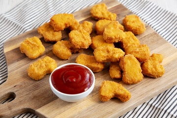 Crunchy Chicken Nuggets with Ketchup on a wooden board, side view.