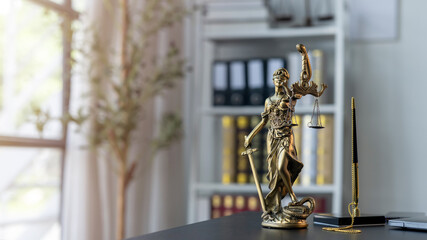 A statue of a woman holding scales and a pen on a desk