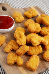 Crunchy Chicken Nuggets with Ketchup on a wooden board, side view.