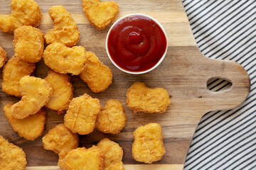 Naklejka premium Crunchy Chicken Nuggets with Ketchup on a wooden board, top view. Flat lay, overhead, from above.